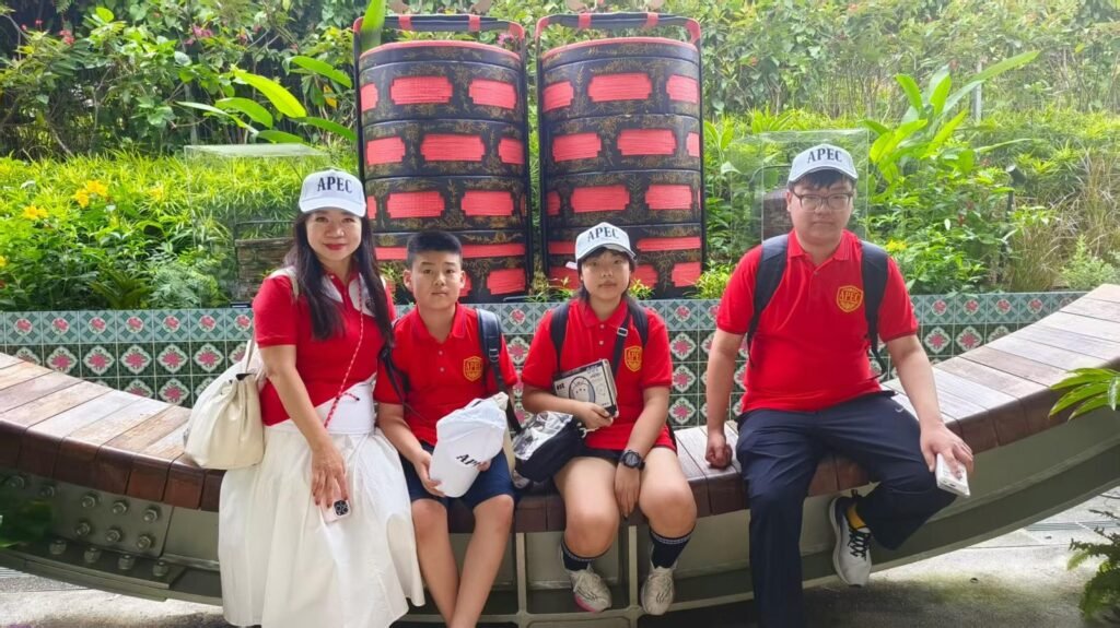Four APEC participants in red shirts seated outdoors
