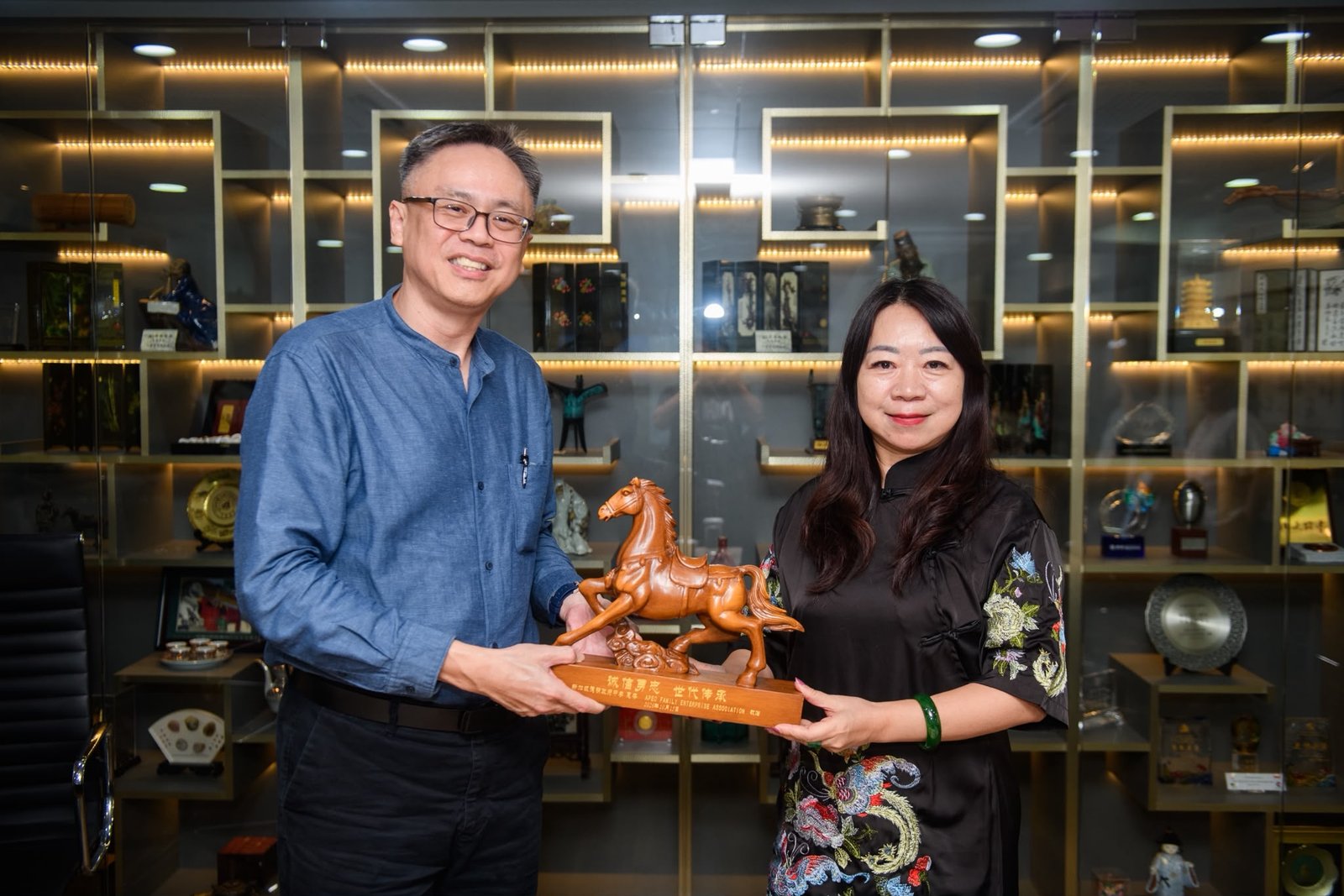 Two people holding a horse sculpture together